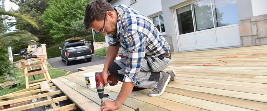a worker installing a new wooden deck on a residential property