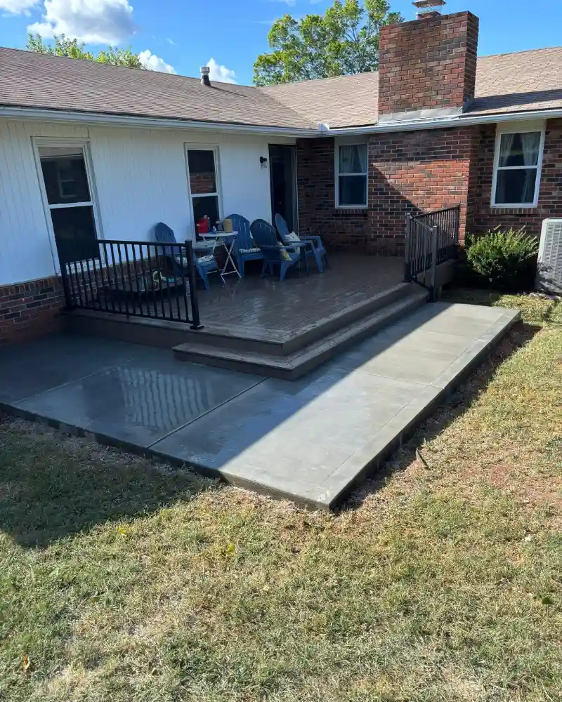 a newly constructed outdoor living space featuring a deck and concrete patio