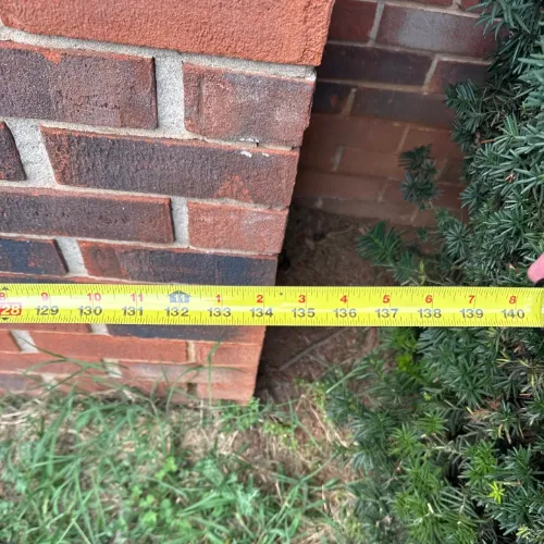 a tape measure indicating a distance of approximately 134 inches to the corner of a brick wall