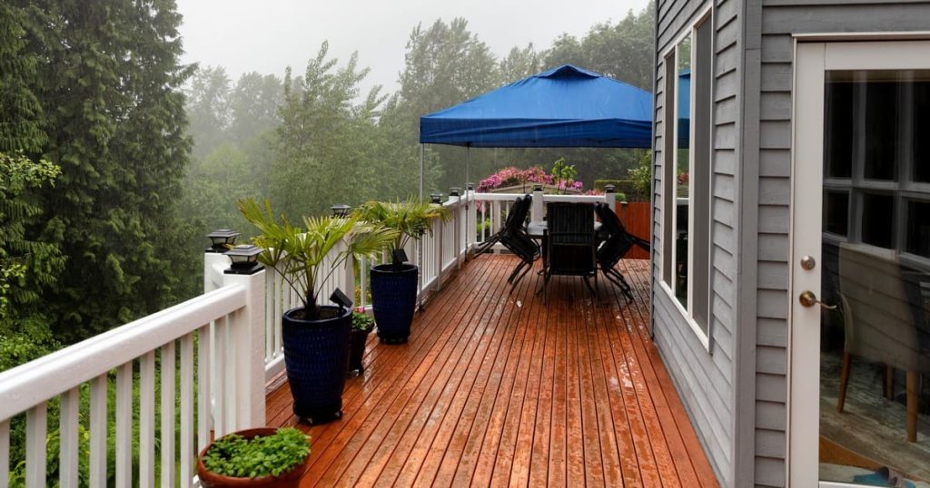 A wooden residential deck in Chattanooga during a heavy spring rainstorm showing water pooling on the surface.