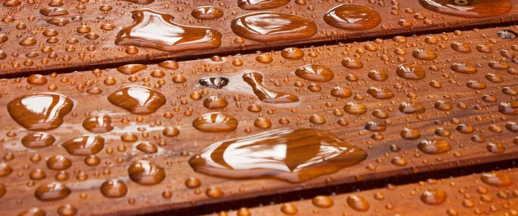Close-up of heavy rain falling on a wooden deck with water droplets bouncing off the timber.