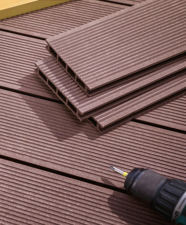 Close-up of stacked brown composite deck boards and a power drill resting on a finished surface, prepped for a deck replacement in Louisville, TN.