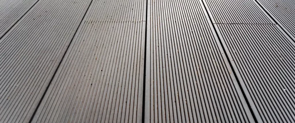 A close-up, angled view showing the straight lines and grooved surface texture of dark grey composite wood deck boards.