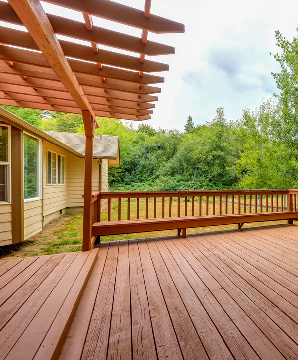 A beautifully finished wooden deck replacement featuring a custom built-in bench and an overhead pergola structure behind a home in Clinton, TN.