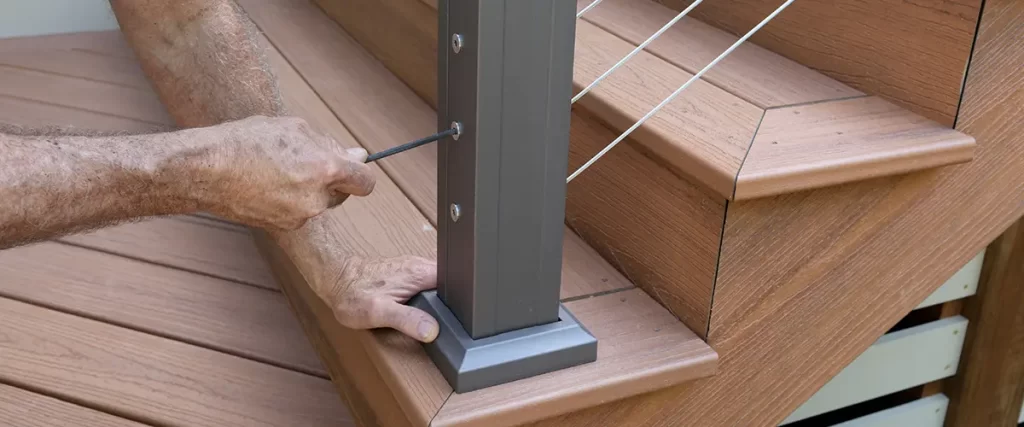 Contractor installing composite deck railing on custom outdoor stairs and decking system