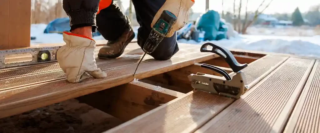 A close-up view of severely weathered and rotting wood with a large square hole in the center requiring immediate deck repair.