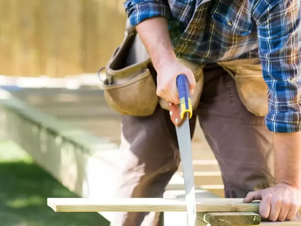 A deck builder cutting a piece of wood