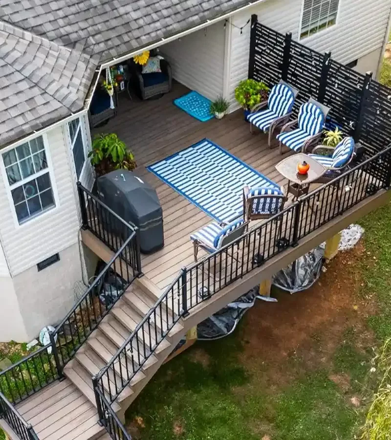 An elevated composite deck featuring black aluminum railings, built-in privacy lattice, and a wide staircase leading to the backyard, showcasing a completed Riverview Decks project.